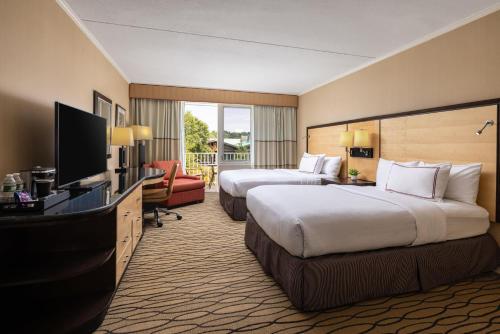 a hotel room with two beds and a flat screen tv at Sleepy Hollow Hotel, a Dolce by Wyndham in Tarrytown