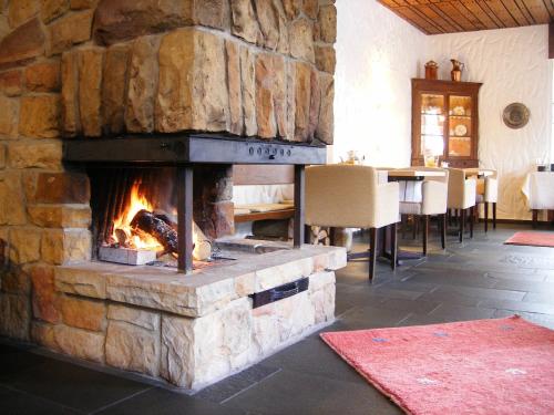 einen Steinkamin im Esszimmer mit einem Tisch in der Unterkunft Hotel Hubertushof in Ibbenbüren