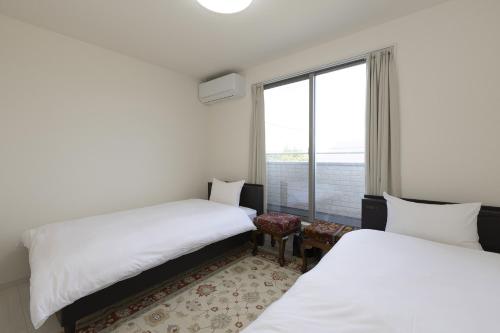 two beds in a room with a window at ev itoshima in Itoshima