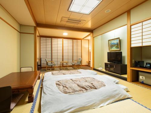 a bedroom with a large bed and a desk and a television at Asagiriso in Toyooka