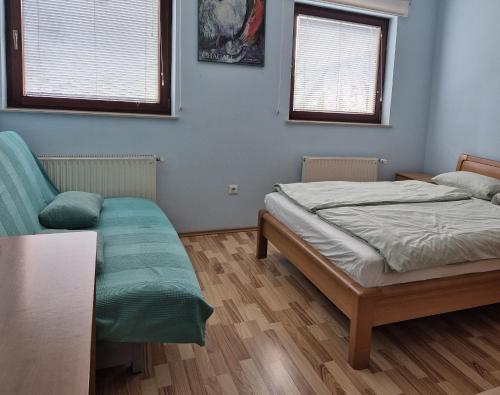 a bedroom with a bed and a couch and two windows at Modrina in Kobarid
