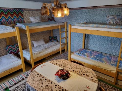 a room with three bunk beds and a table at Onodilak Guesthouse - Vendégház in Bîrzava