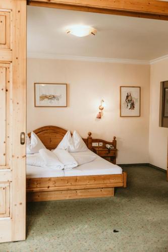 una camera da letto con un letto di legno con lenzuola bianche di Hotel Steffner-Wallner a Mauterndorf