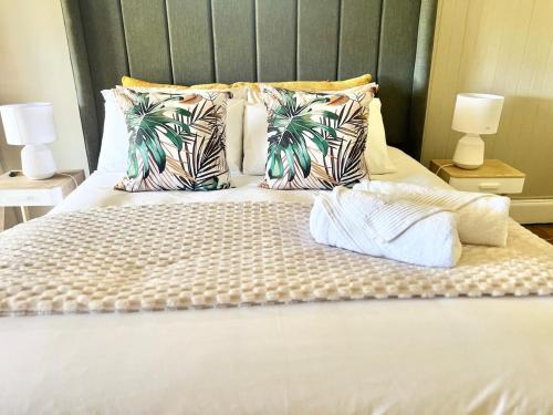 a bedroom with a bed with white sheets and tropical pillows at Briar & Bloom 1 in Hilton