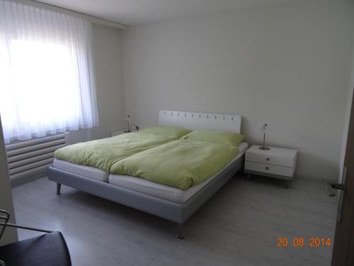 Un dormitorio con una cama con una manta verde. en Haus Montanara, en Unterbäch