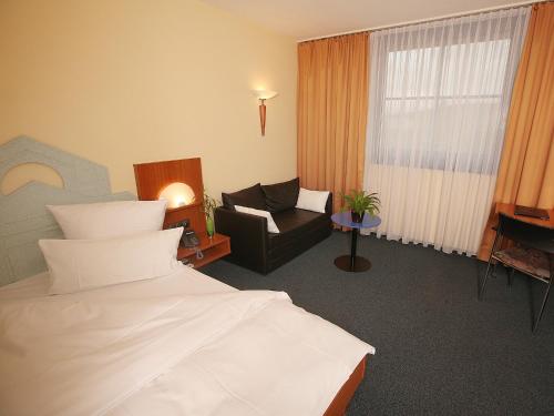 Habitación de hotel con cama y silla en Transmar Travel Hotel en Bindlach