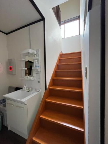 a staircase leading up to a bathroom with a sink at 民泊 シェアハウス北浦 in Senboku