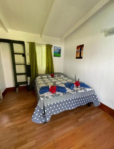a bedroom with a bed with red flowers on it at Hostal y Cabañas Pua Vaenga in Hanga Roa