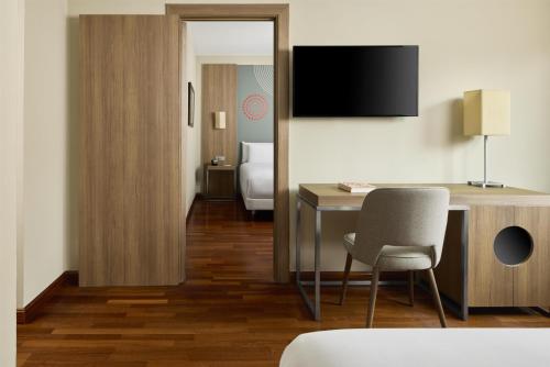 ein Hotelzimmer mit Schreibtisch und Fernseher in der Unterkunft iStay by NH Zaragoza Sport Hotel in Saragossa