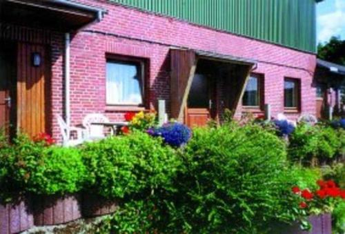 a pink brick house with a bunch of bushes at Ferienhof Budach - Landurlaub vor den Toren Flensburgs in Handewitt