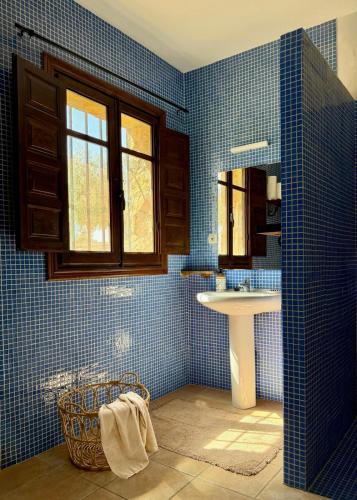a blue tiled bathroom with a sink and a mirror at Cortijo Sol y Olivo spacious exclusive private pool retreat in Algarinejo