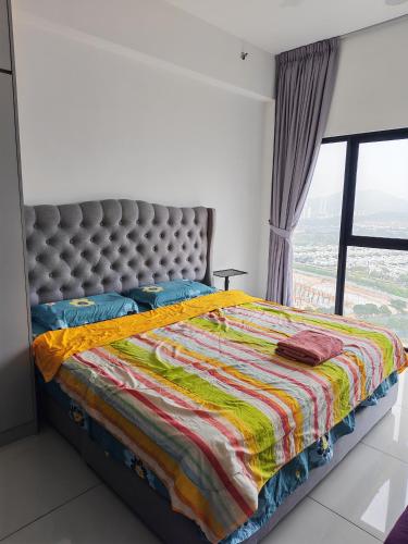 a bedroom with a bed with a quilt and a window at Eduscentral Stanford, Setia Alam in Shah Alam