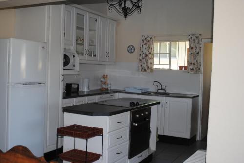 una cucina con mobili bianchi e un piano di lavoro nero di 37 Valley View Cottage a Underberg