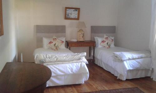 una camera con due letti con lenzuola bianche e un tavolo di 37 Valley View Cottage a Underberg
