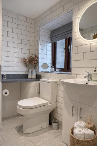 a white bathroom with a toilet and a sink at Careful Cottage in Crediton