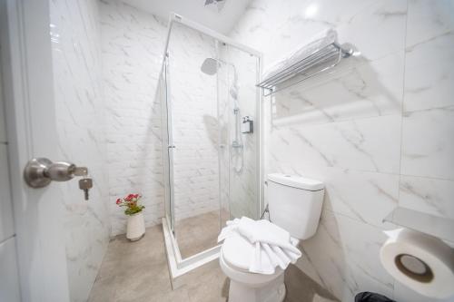 a white bathroom with a toilet and a shower at Horison IJ Kudus in Kudus