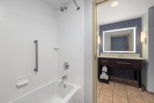 a bathroom with a tub and a sink and a mirror at Homewood Suites by Hilton West Des Moines/SW Mall Area in West Des Moines