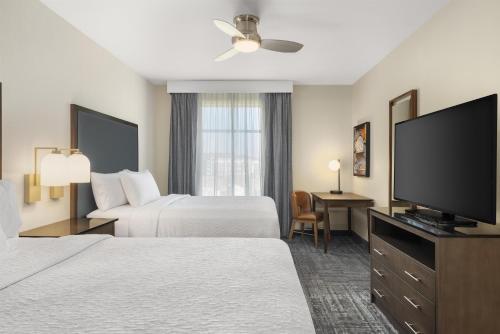 a hotel room with two beds and a flat screen tv at Homewood Suites by Hilton West Des Moines/SW Mall Area in West Des Moines