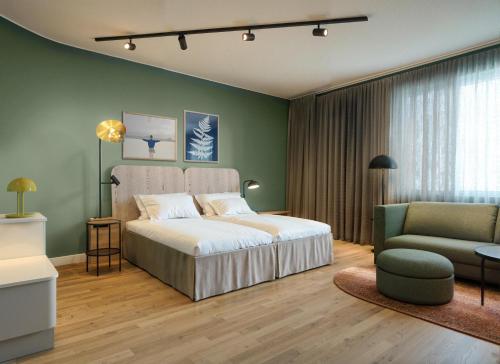 a bedroom with a bed and a couch and a chair at Scandic Charlottenburg in Berlin