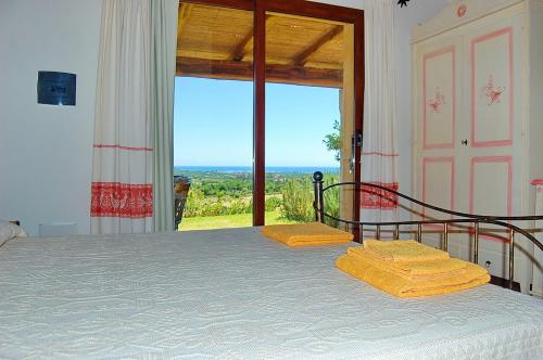 1 dormitorio con cama y ventana grande en Li Teggi Turismo Rurale, en San Teodoro