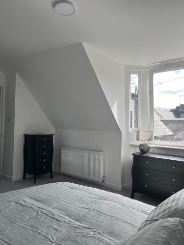 a bedroom with a bed and a dresser and a window at Upper Mill Apartment in Newmilns