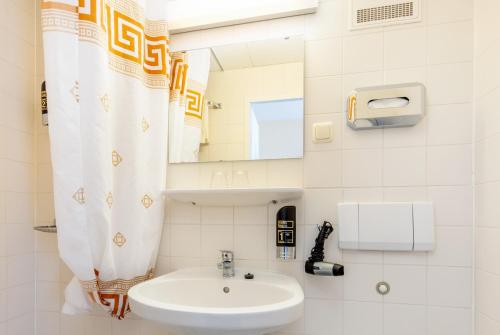 a white bathroom with a sink and a mirror at Hotel Waldperle in Göhren