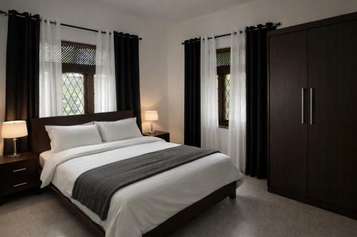 a bedroom with a large bed and two windows at Long Villa in Kandy