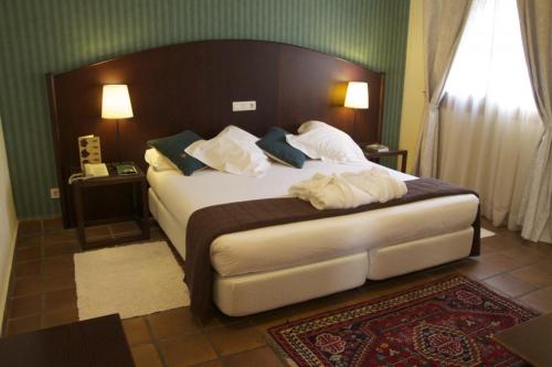 1 dormitorio con 1 cama grande con sábanas y almohadas blancas en Hotel L'Estació, en Bocairent