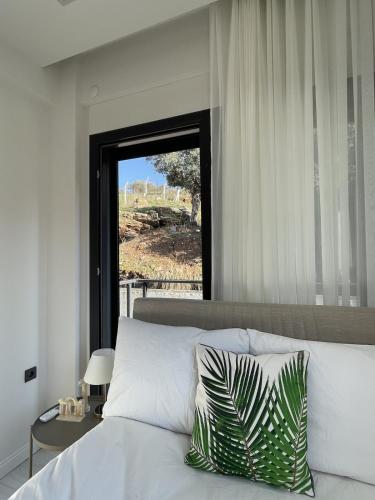 a bedroom with a white bed with a window at Villa Gaia in Selçuk