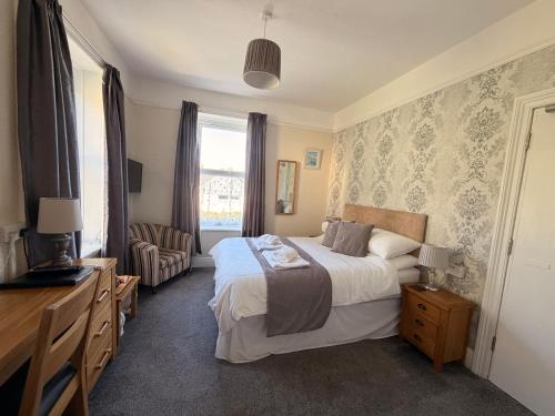 a bedroom with a bed and a chair and a window at Cairn House in Ilfracombe