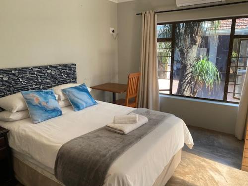 a bedroom with a bed with blue pillows and a window at Waveside Guesthouse in Durban