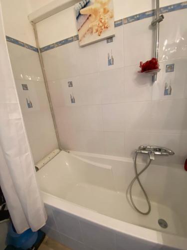 a white bath tub with a shower curtain in a bathroom at Pause Soleil in Gruissan