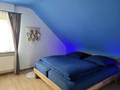 a bed in a room with a blue wall at Ferienwohnung Amano in Fischbach