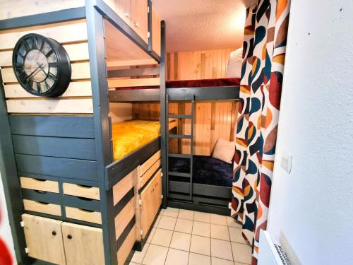 a small room with bunk beds and a clock at Le TERMINUS in Saint-Cyprien-Plage