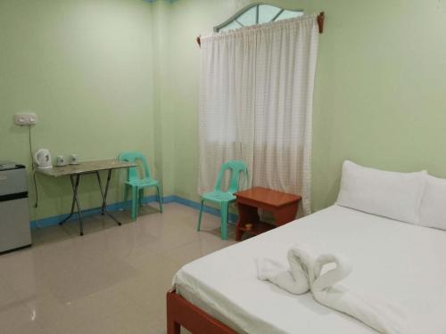 a bedroom with a bed and two chairs and a table at Hidden Valley Guest House in Malapascua Island