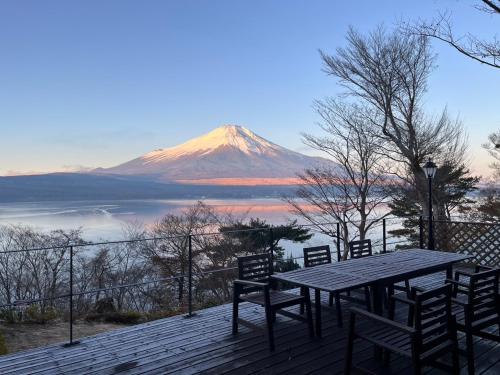 a table and chairs on a deck with a mountain at Buckeye House by the lake in Yamanakako