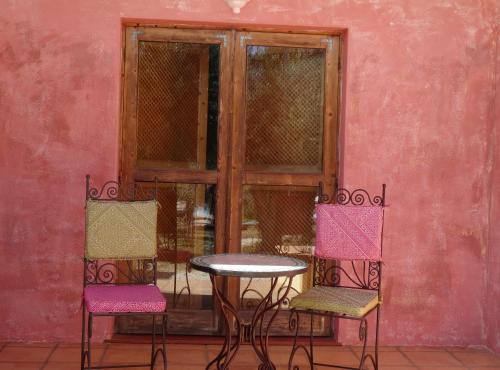a table and two chairs in front of a pink wall at Hotel de Charme Capela das Artes in Armação de Pêra