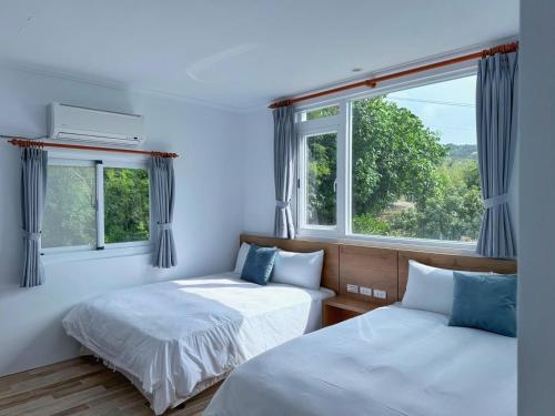 two beds in a room with two windows at 純粹Home 民宿 in Shui-wa-chüeh