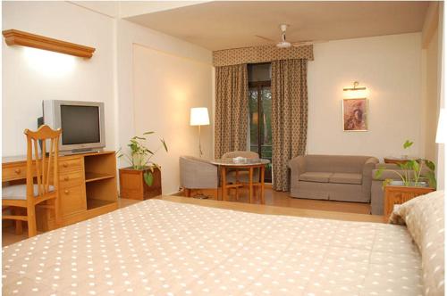 a bedroom with a bed and a living room with a television at Hotel Margala in Islamabad