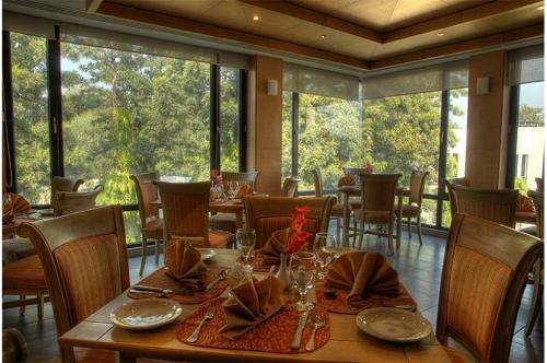 a dining room with a table and chairs and windows at Hotel Margala in Islamabad