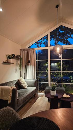 a living room with a couch and a large window at Bungalow type Korhoen 4p in Otterlo