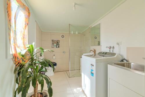 a bathroom with a sink and a washing machine at Zamenhof River Cabin - Peaceful Farm Escape - Pets Welcome in Yass