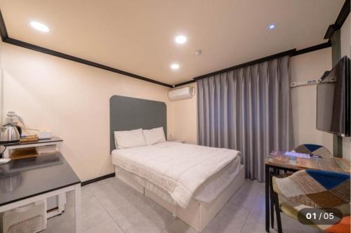 a small bedroom with a bed and a table at Prince Motel in Busan