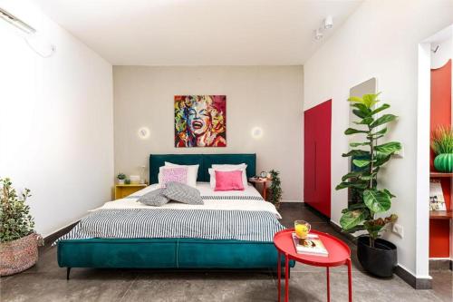a bedroom with a green bed and a red table at דירת סטודיו שקטה עם גקוזי בלב ראשלצ in Rishon LeẔiyyon