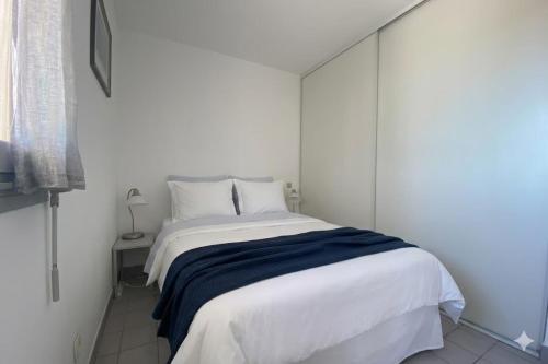 a bedroom with a white bed with a blue blanket at Sea & Relaxation Stay in Frontignan