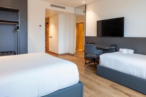 a hotel room with two beds and a desk at SB Madrid Norte in San Sebastián de los Reyes
