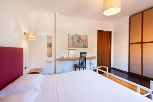 a bedroom with a white bed and a desk at Baveno Beach - Charming Flat With Garden in Baveno