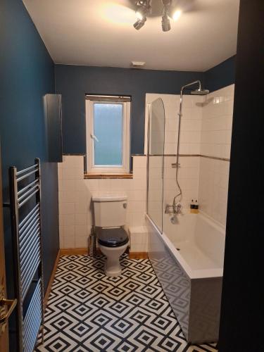a bathroom with a toilet and a bath tub at The Curling Pond, Dalmally Road, Inveraray in Inveraray
