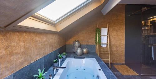 a bathroom with a large bath tub and a skylight at Ospa in Hamois
