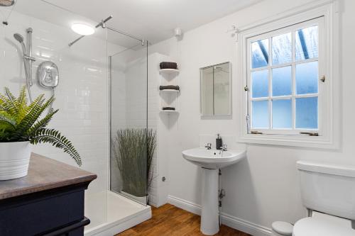 a white bathroom with a sink and a shower at The Courtyard in Exeter